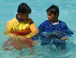 swimming lesson by lifeguard in red and yellow swimwear.